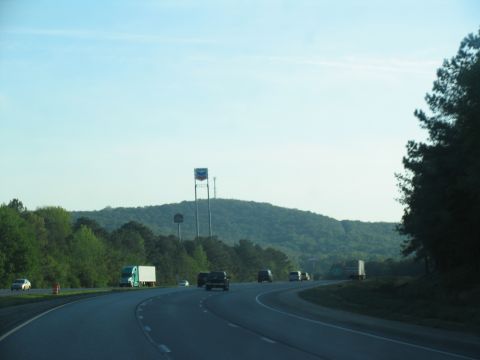 1995 Ford C-350 (Centurion Conversions) - Driving on a highway with several vehicles and a large Chevron sign visible in the distance.