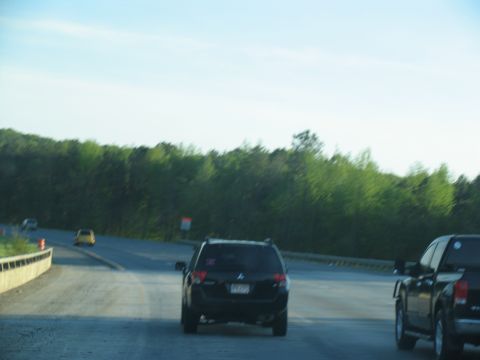 1995 Ford C-350 (Centurion Conversions) - Multiple vehicles drive on a highway with trees in the background.