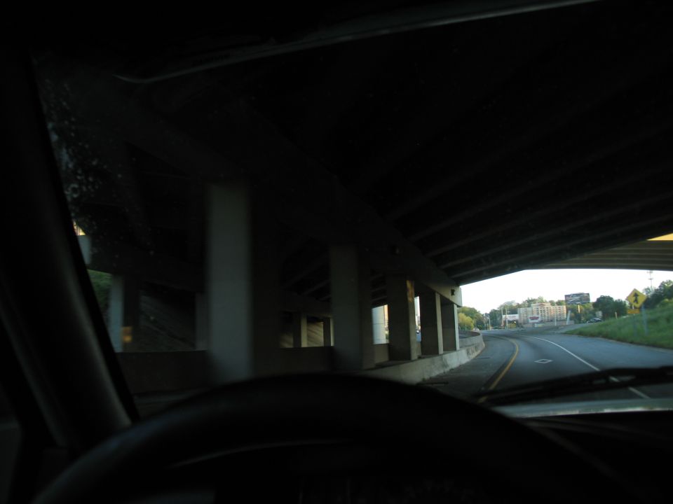 Interior view from a vehicle's dashboard looking out at a highway underpass