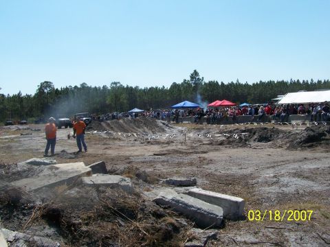 1989 Ford Bronco - A crowd watches vehicles navigate a challenging off-road course on a sunny day.