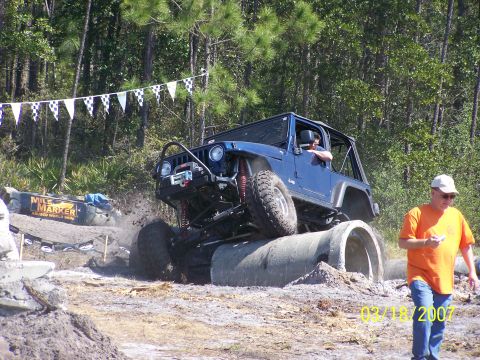 1989 Ford Bronco - A blue Jeep navigates a challenging obstacle course with concrete pipes.