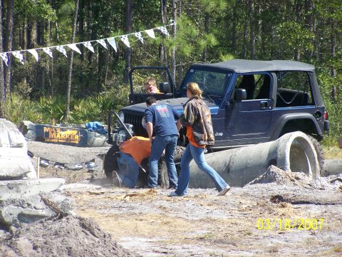 1989 Ford Bronco - A Jeep Wrangler is stuck on a concrete pipe during an off-road event.