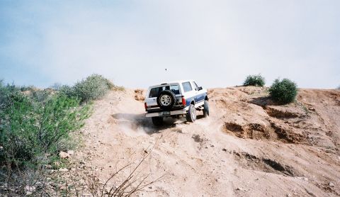 1996 Ford Bronco - This 1996 Ford Bronco is navigating a steep, sandy incline in an off-road environment.
