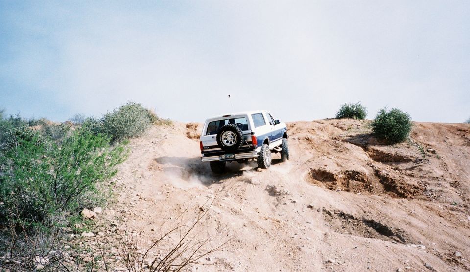 1996 Ford Bronco climbing a dusty dirt hill off-road