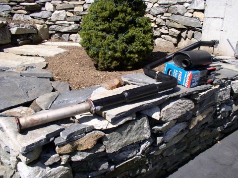 1996 Ford Probe - An exhaust system part is laid out on a stone wall next to a Makita tool box.