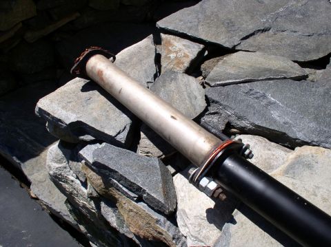 1996 Ford Probe - A section of exhaust pipe, likely removed from a vehicle, is placed on a stone surface.