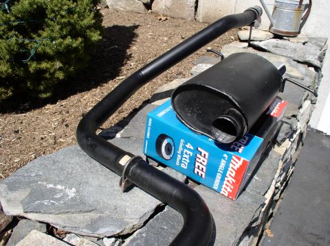 1996 Ford Probe - Exhaust system components are laid out on a stone wall, with a power tool box nearby.