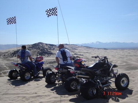 1981 Ford Bronco - Riders on ATVs with checkered flags enjoy a day on the sand dunes.