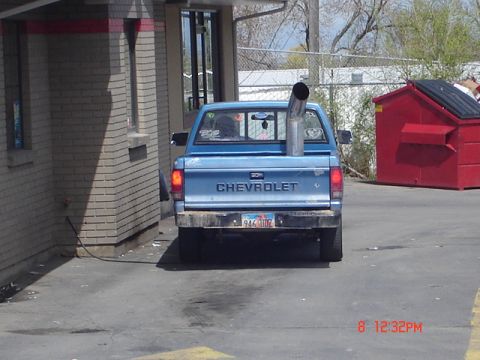 1981 Ford Bronco - A blue Chevrolet pickup truck is seen from the rear, parked next to a red dumpster.