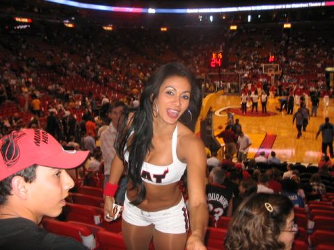 1991 Ford Bronco - A woman in a cheerleader outfit poses at a basketball game, with a Miami Heat hat in the foreground.
