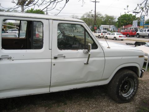 1986 Ford Bronco - This four-door pickup truck shows signs of wear and tear, with visible dents and rust along the lower body panels.