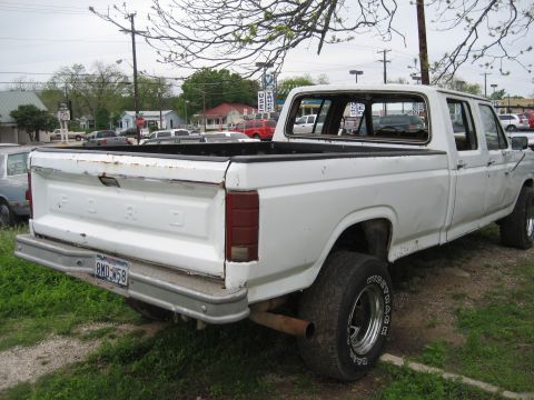 1986 Ford Bronco - This white Ford pickup truck is seen from the rear, parked outdoors.