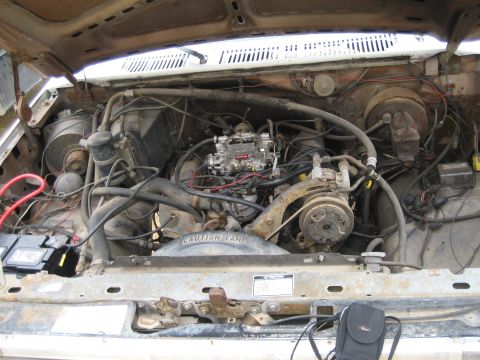 1986 Ford Bronco - The engine bay of a vehicle shows a V8 engine with a carburetor and AC compressor, appearing to be from the mid-1980s.