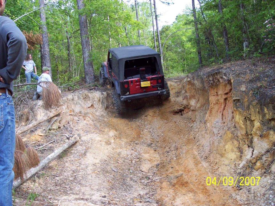 Jeep Wrangler going down a steep dirt trail with people watching