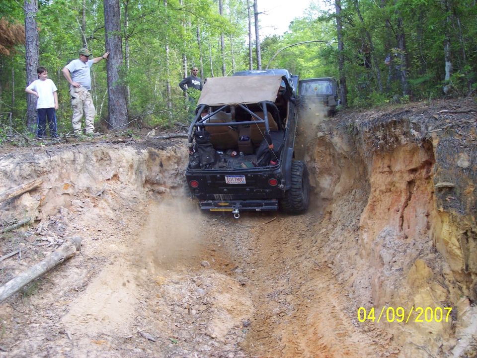 Off-road vehicle descending steep dirt embankment, kicking up dust