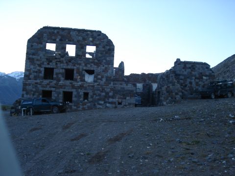 1986 Ford Bronco - Two SUVs are parked near the ruins of a large stone building on a rocky hillside.