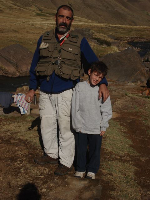 1986 Ford Bronco - A man and a young boy pose for a photo in a , natural landscape with hills and water visible.