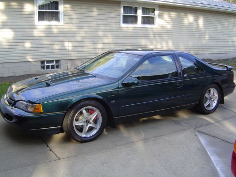 1995 Ford Thunderbird - A dark green coupe, possibly a 1994 model, is shown from a three-quarter front angle.