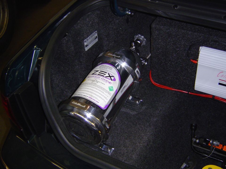 Nitrous oxide tank with ZEX label in car trunk next to an amplifier