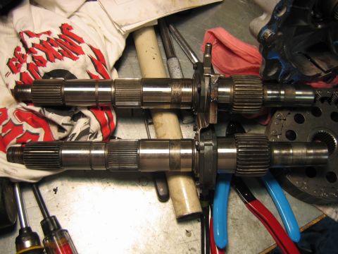 1992 Ford Bronco - Two transmission or transfer case output shafts laid side by side on a workbench, showing splined ends and machined bearing surfaces. Also…