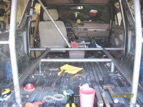1994 Ford Bronco - The interior of a 1994 Ford Bronco shows the progress of a new rear roll cage installation, with various tools and metal parts visible on t…
