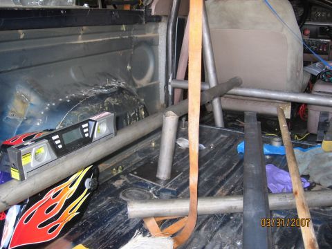 1994 Ford Bronco - The interior of a vehicle shows a roll cage installation with various tools and a digital level.