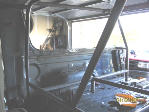 1994 Ford Bronco - A custom roll cage is being installed inside a vehicle, with tools visible on the floor.