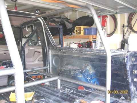 1994 Ford Bronco - The interior of a Ford Bronco, modified with a roll cage, is visible in a garage setting.
