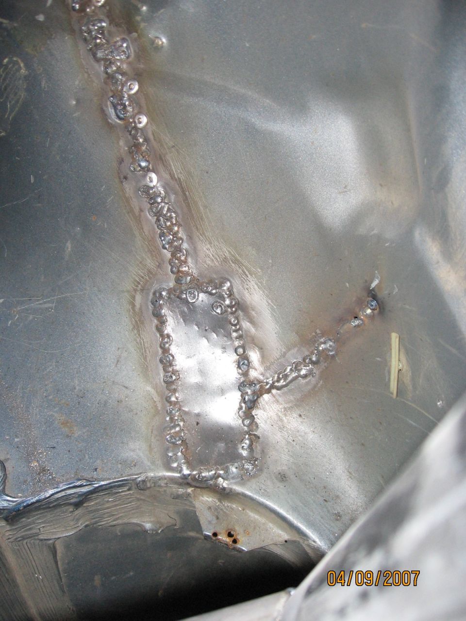 Rectangular sheet metal patch panel MIG welded into bare steel rust repair, welds unground