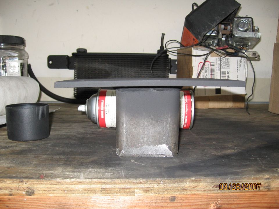 Fabricated steel bracket of square tube welded to a flat plate on a workbench