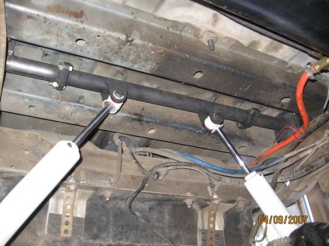 1994 Ford Bronco - Underside view of a vehicle's suspension system, showing white shock absorbers and a black sway bar.