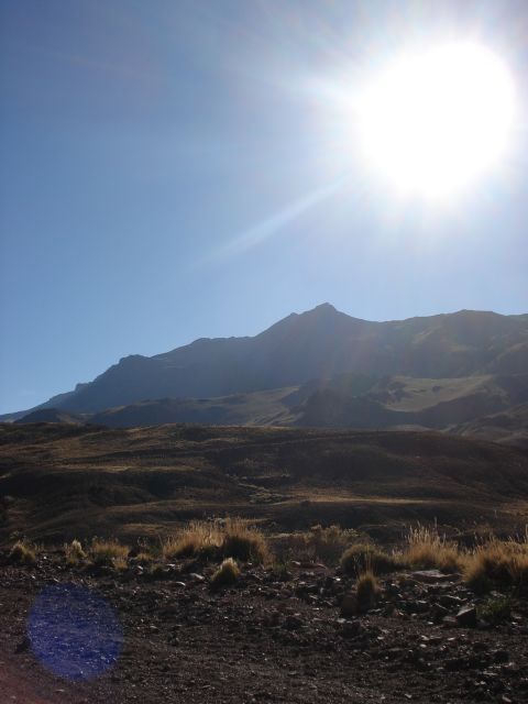 1986 Ford Bronco - A vast mountain range is bathed in sunlight under a clear blue sky.