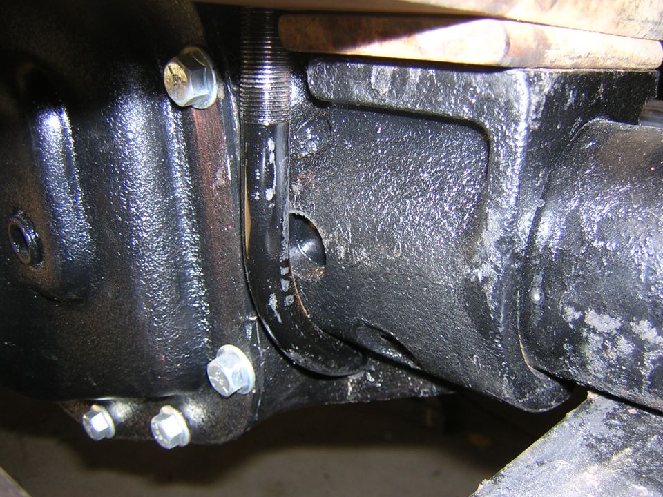 Underside close-up of black-painted axle housing and differential cover bolts with U-bolt and leaf spring on a Ford F-250