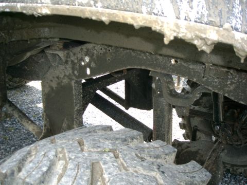 1991 Chevrolet Suburban - Close-up view of the dirty undercarriage and tire of a vehicle.