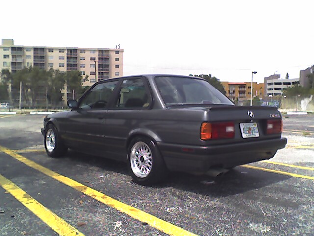 Grey BMW E30 coupe on basketweave wheels parked in a striped lot