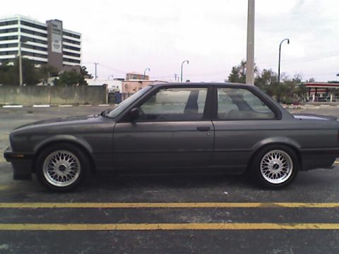1989 BMW 3 Series - Side view of a dark gray coupe with distinctive wheels, parked in a lot.