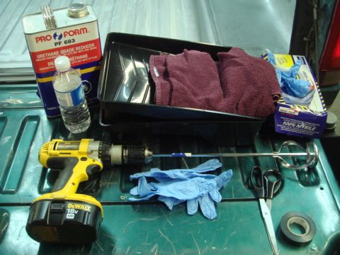 1996 Ford Bronco - Various automotive supplies are laid out on a green truck bed, including a drill and paint reducer.