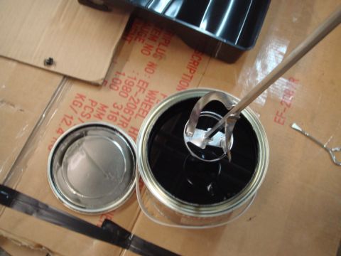 1996 Ford Bronco - A can of black paint is shown with a mixing attachment, resting on cardboard packaging with visible text and numbers.