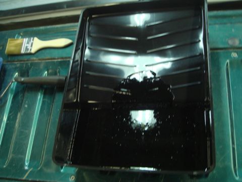 1996 Ford Bronco - A paint tray filled with black paint sits on a green surface next to a brush and roller.