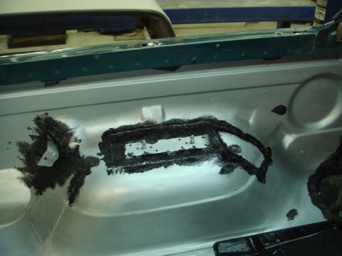 1996 Ford Bronco - Close-up view of a vehicle's interior metal panel, showing sealant application and mounting points.