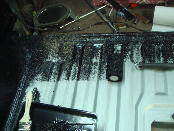 Applying black coating to the ribbed floor of a vehicle interior with a brush and roller