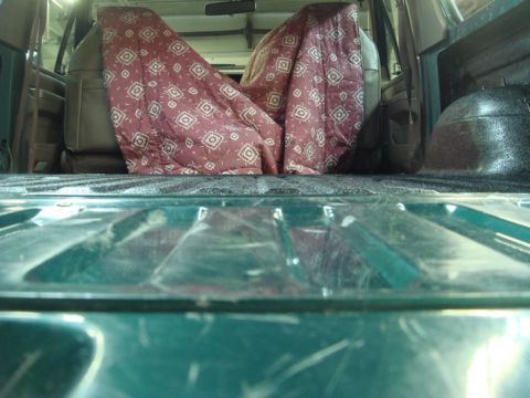 1996 Ford Bronco - The interior of a vehicle, with seats covered by a patterned blanket, seen from the cargo area.