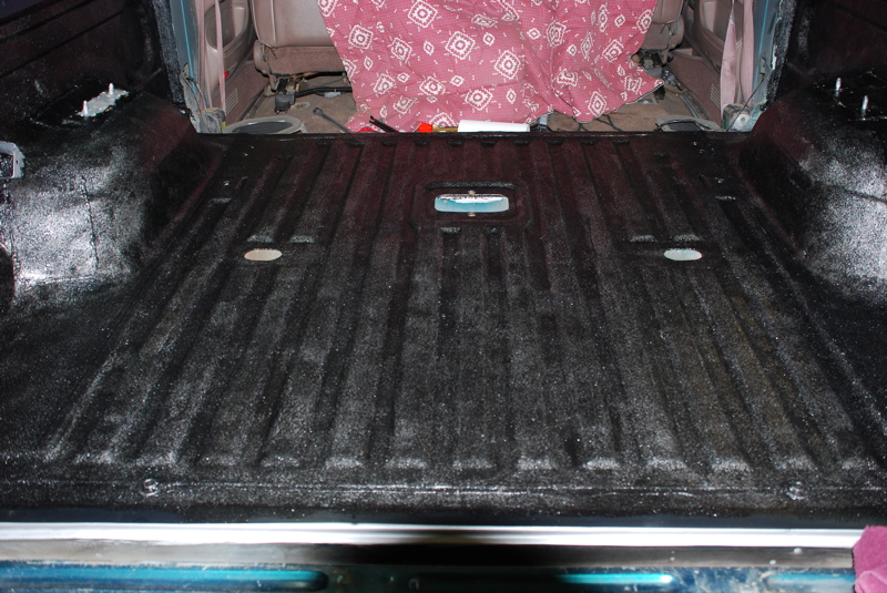 Truck bed liner with textured black coating and visible tie-down points
