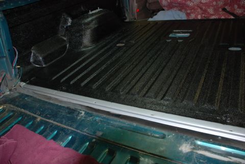 1996 Ford Bronco - The interior of a truck bed is shown with a textured black Herculiner coating applied to the floor and sides.