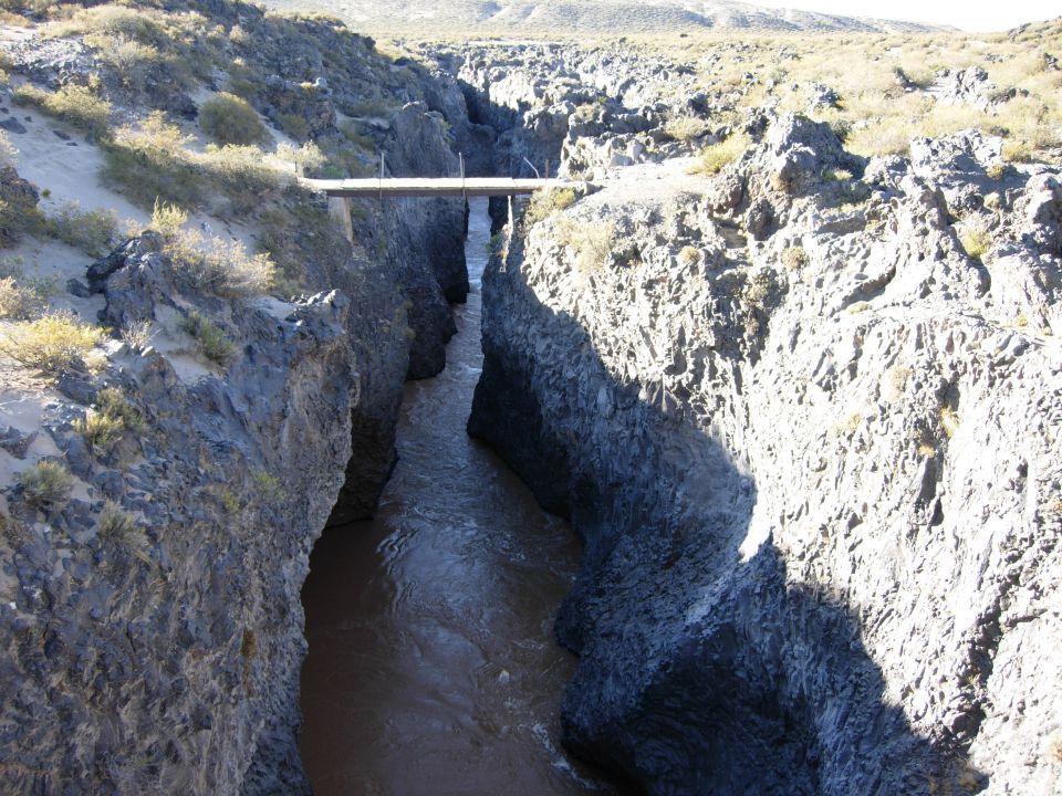 Canyon with a river flowing through it and a simple bridge spanning the gap