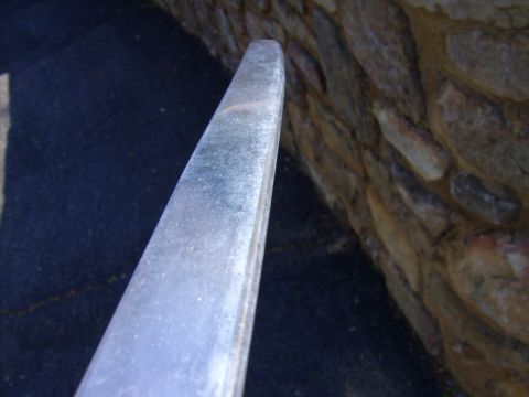 1982 Ford Crown Victoria LTD - Close-up of a chrome trim piece, possibly from a vehicle, set against a textured stone wall.