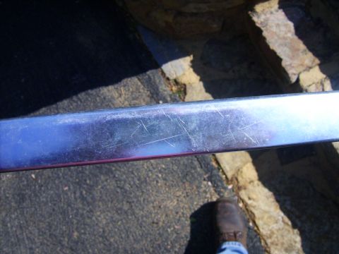 1982 Ford Crown Victoria LTD - Close-up of a scratched chrome trim piece, likely from a car's exterior.