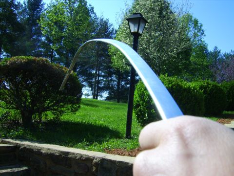 1982 Ford Crown Victoria LTD - A chrome trim piece is held up in front of a landscaped yard with a lamppost.