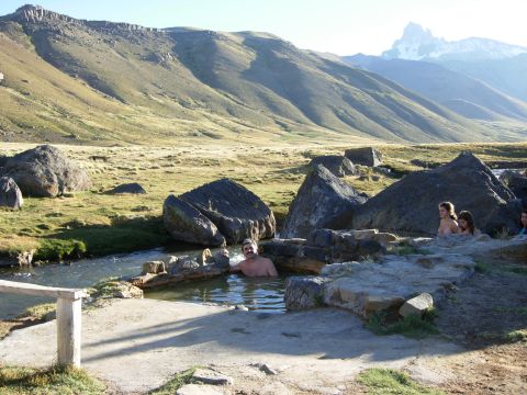 1986 Ford Bronco - A scenic view of a natural hot spring in a mountainous landscape, with several people enjoying the warm water.