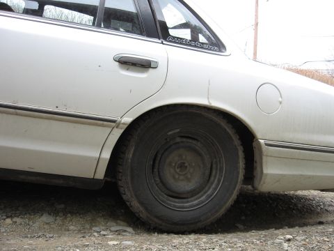 1992 Ford Crown Victoria - The rear quarter panel and door of a white 1992 Ford Crown Victoria are visible from the side.